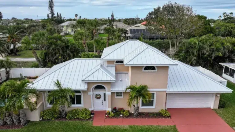 Beige Florida home with new white metal roof and tropical landscaping